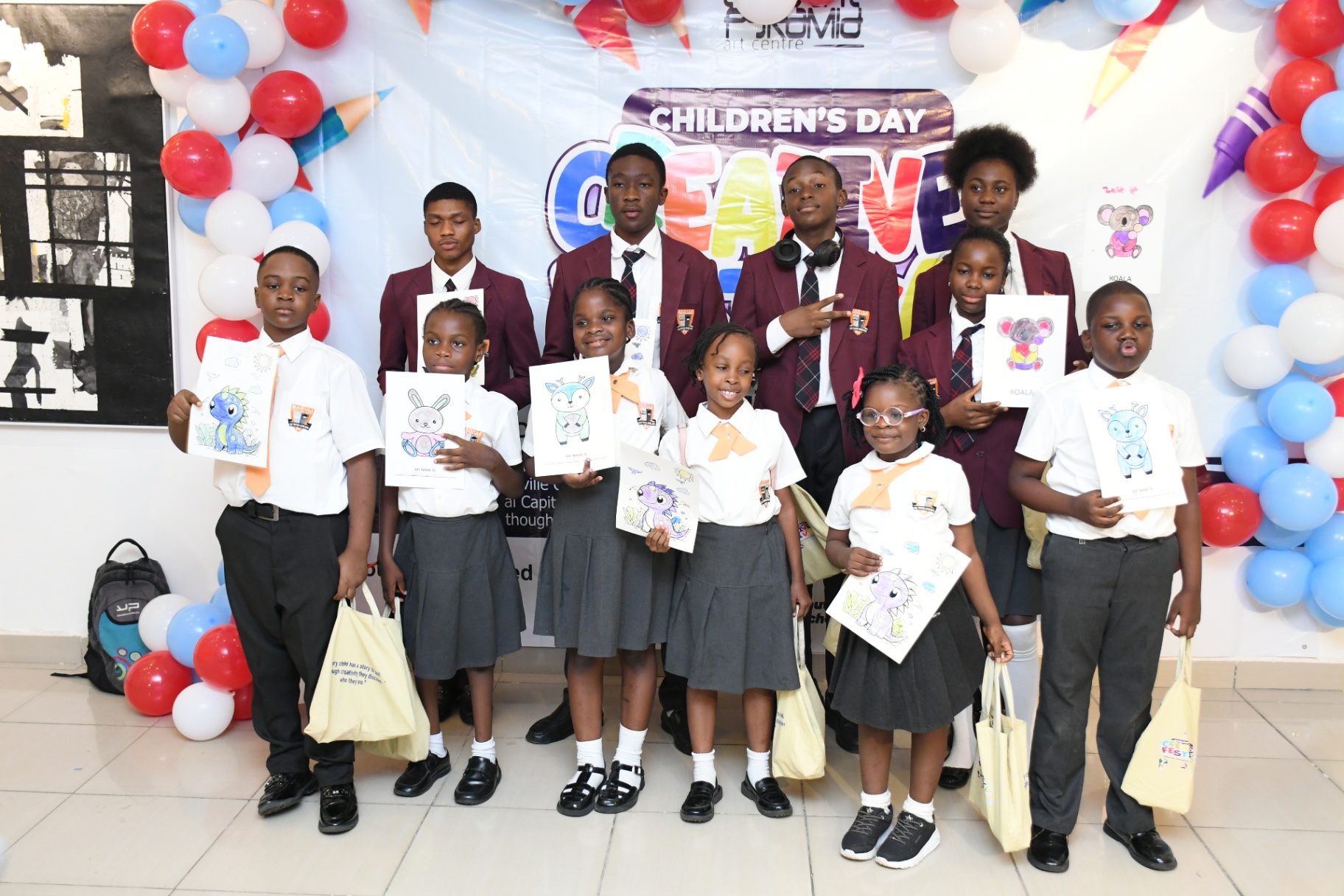 Another group portrait of children proudly displaying their coloured artworks