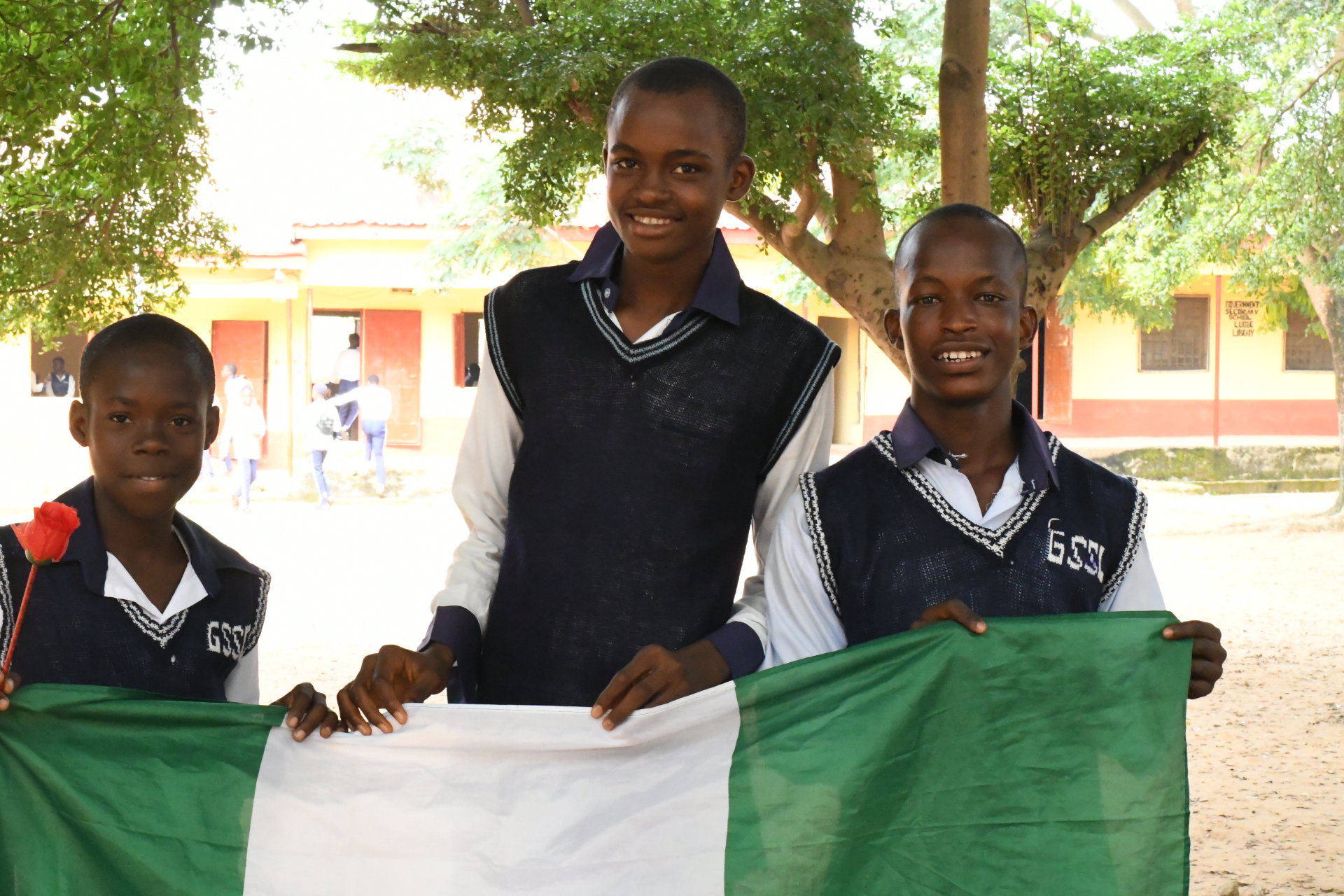 Three Nigerian secondary school students holding a national flag