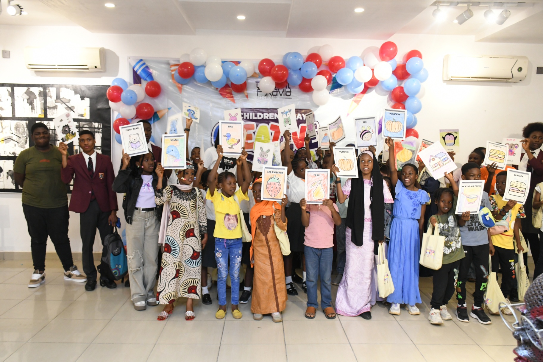 Children holding up their coloured drawings at Thought Pyramid Art Centre